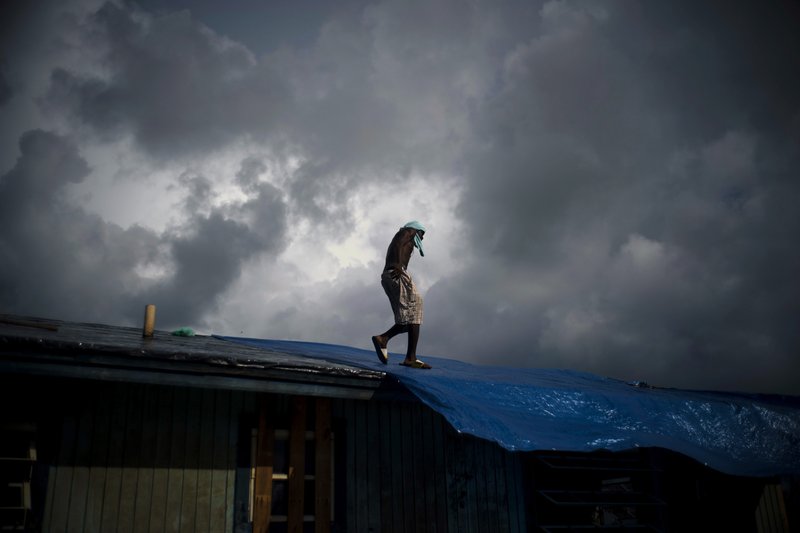 Trevon Laing walks the roof of his house to repair the damage made by Hurricane Dorian, in Gold Rock Creek, Grand Bahama, Bahamas, Thursday Sept. 12, 2019.  (AP Photo / Ramon Espinosa)