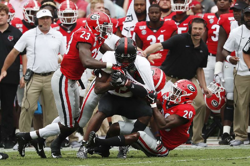 Arkansas State wide receiver Kirk Merritt (middle) is dragged down by Georgia defensive backs Mark Webb (23) and J.R. Reed during the Red Wolves’ 55-0 loss to the No. 3 Bulldogs on Saturday in Athens, Ga. Merritt finished with six catches for 25 yards.