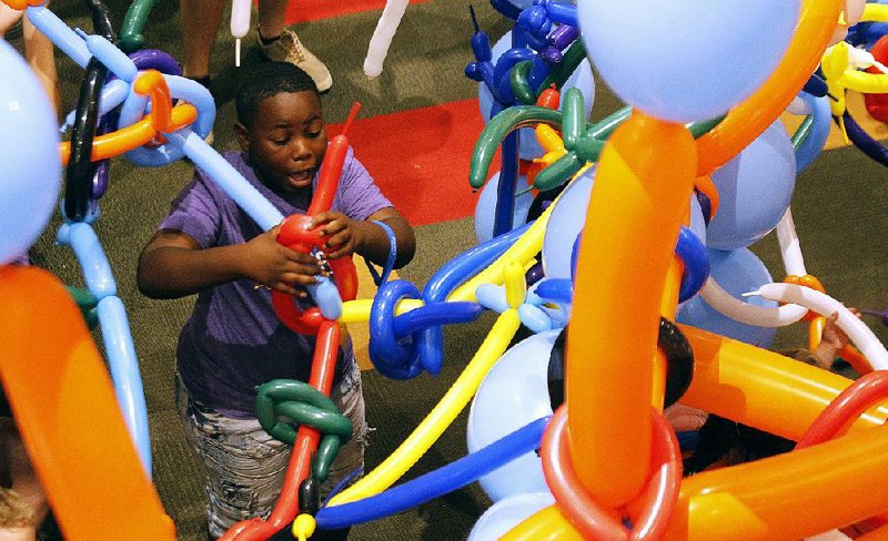 Tayveon Moore, 11, gets his balloon tangled up while making his way through the balloon maze Saturday during the Museum of Discovery’s Tinkerfest in Little Rock. More photos are available at www.arkansasonline.com/915tinker/