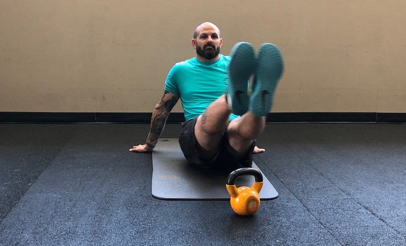 Personal trainer Christopher "Smitty" Smith demonstrates the Side to Side V Up exercise in a quiet corner at Little Rock Athletic Club. (Arkansas Democrat-Gazette/CELIA STOREY)