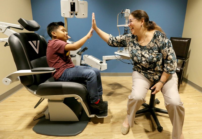 NWA Democrat-Gazette/DAVID GOTTSCHALK Alexander Garcia, 8, receives a high five Sept. 9 from Dr. Sharon Napier following an eye examination at Vold Vision in Fayetteville. Napier is the first pediatric ophthalmologist in Northwest Arkansas.