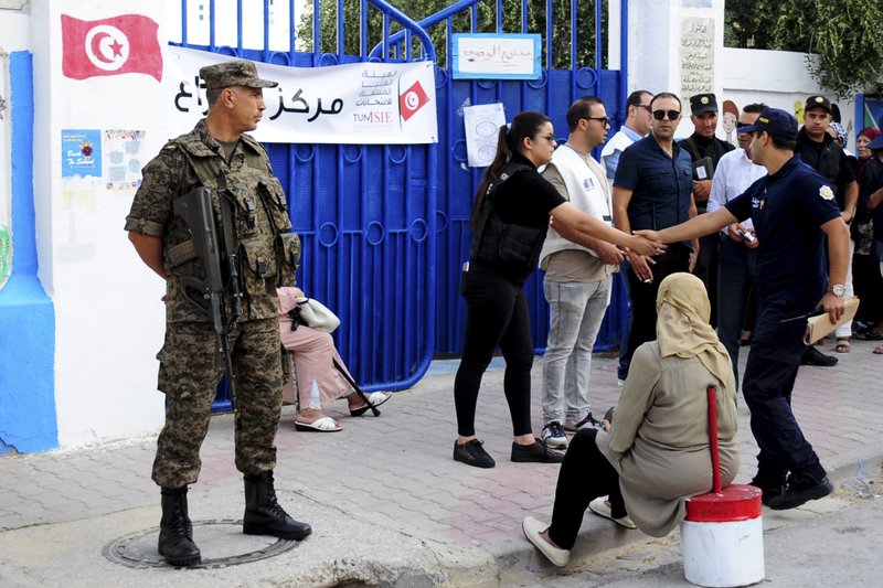 Security forces stand guard as voters queue outside a polling station during the first round of the presidential election, in La Marsa, outside Tunis, Tunisia, Sunday Sept. 15, 2019. Tunisians are casting ballots in their North African country's second democratic presidential election, choosing among 26 candidates for a leader who can safeguard its young democracy and tackle its unemployment, corruption and economic despair. (AP Photo/Hassene Dridi)