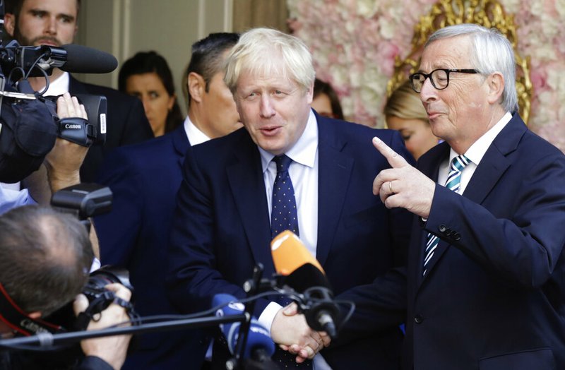 European Commission President Jean-Claude Juncker, right, speaks with the media as he shakes hands with British Prime Minister Boris Johnson prior to a meeting at a restaurant in Luxembourg, Monday, Sept. 16, 2019. British Prime Minister Boris Johnson was holding his first meeting with European Commission President Jean-Claude Juncker on Monday in search of a longshot Brexit deal. (AP Photo/Olivier Matthys)