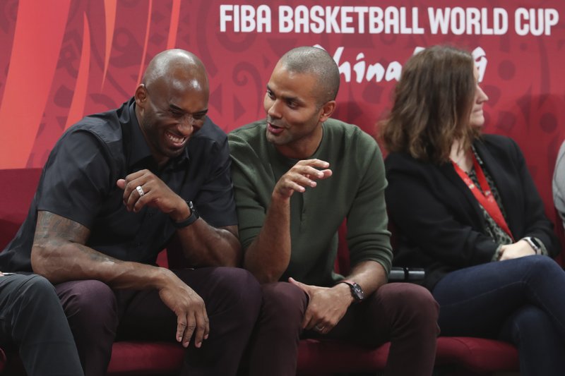 Former NBA players Kobe Bryant, left, and Tony Parker talk during the first-place match between Spain and Argentina in the FIBA Basketball World Cup at the Cadillac Arena in Beijing, Sunday, Sept. 15, 2019. (AP Photo/Ng Han Guan)