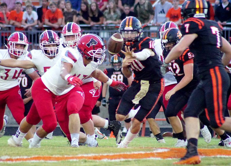 Westside Eagle Observer/RANDY MOLL With Farmington senior Josh Stettmeier closing in for the tackle, Gravette quarterback Cy Hilger pushes the ball off to Gravette runningback Chace Austin during play between Gravette and Farmington in Lion Stadium on Friday, Sept. 13, 2019.