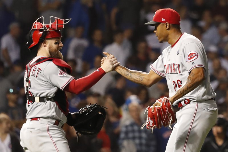 Cincinnati Reds catcher Tucker Barnhart and relief pitcher Raisel Iglesias celebrate the team's 4-2 win over the Chicago Cubs in a baseball game Tuesday, Sept. 17, 2019, in Chicago. (AP Photo/Charles Rex Arbogast)