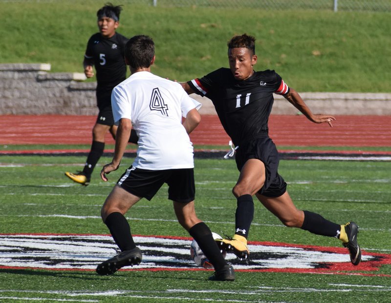 RICK PECK/SPECIAL TO MCDONALD COUNTY PRESS McDonald County's Eh Doh Say dribbles past College Height's Noah Friend during the Mustangs 3-0 win on Sept. 10 at MCHS.