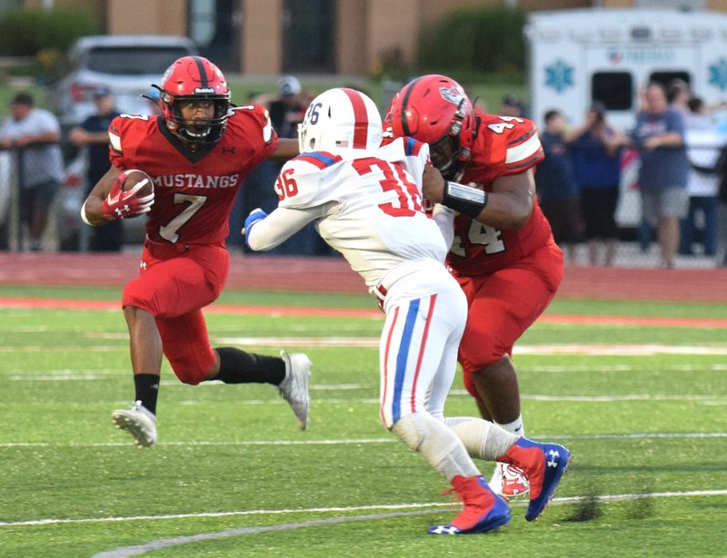 RICK PECK/SPECIAL TO MCDONALD COUNTY PRESS McDonald County running back Junior Teriek uses the block of teammate Junior Eliam on East Newton's Noah Breshears for a short gain during the Mustangs' 25-22 win on Sept. 13 at MCHS.