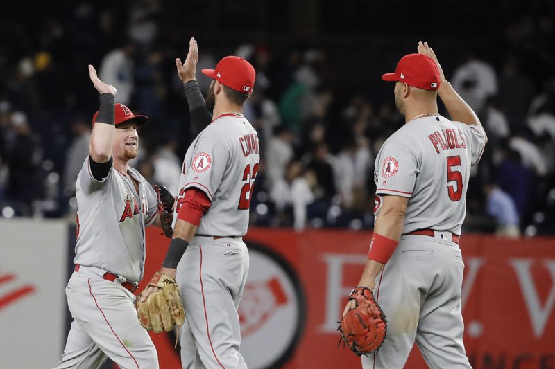 Los Angeles Angels' Kole Calhoun, left, celebrates with Kaleb Cowart (22) and Albert Pujols (5) after Wednesday's game against the New York Yankees in New York. The Angels won 3-2. Photo by Frank Franklin II of The Associated Press