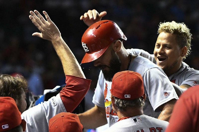 Matt Carpenter of the St. Louis Cardinals is congratulated by  teammates as he returns to the dugout after hitting a home run in the 10th inning of the Cardinals’ 5-4 victory over the Chicago Cubs on Thursday night at Wrigley Field in Chicago. 