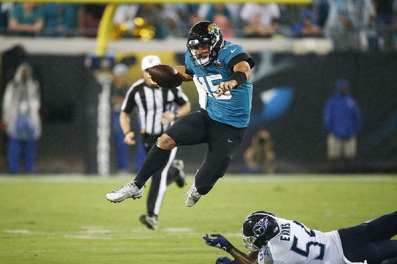 Jacksonville Jaguars quarterback Gardner Minshew leaps over a Tennessee Titans defender during the Jaguars’ victory Thursday night. Minshew passed for 204 yards and two touchdowns. 