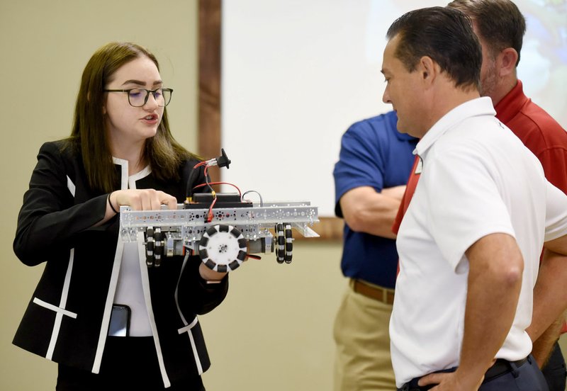 NWA Arkansas Democrat-Gazette/DAVID GOTTSCHALK Summer Garner (left), a senior at the Tyson School of Innovation and Diva Force team member, describes Thursday one of the robots at the new Springdale Robotics Center. The center, open to students ages 5-18, is a nonprofit group providing youth a facility to participate in STEM activities, specifically robotics. The center offers a full machine shop, access to build robots, program, computer-aided design and learning electronic skills through hands-on learning.