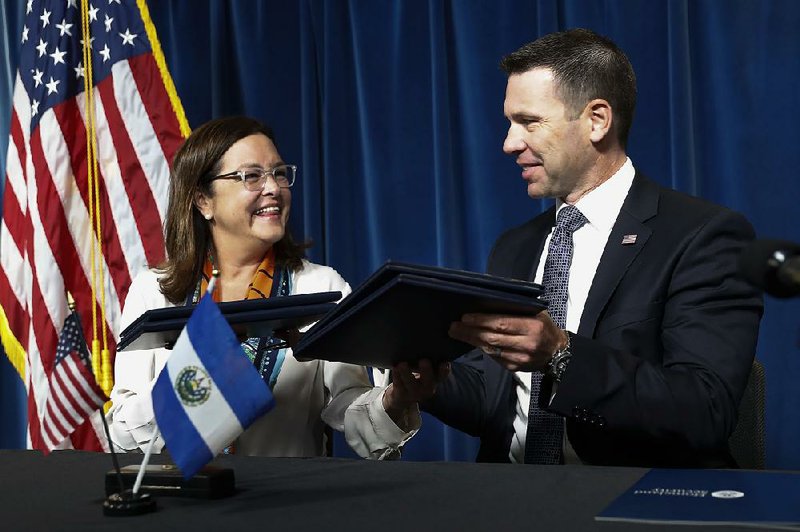 Acting Homeland Security Secretary Kevin McAleenan exchanges folders with El Salvadoran Foreign Affairs Minister Alexandra Hill Tinoco after signing an immigration agreement Friday at U.S. Customs and Border Protection headquarters in Washington. 