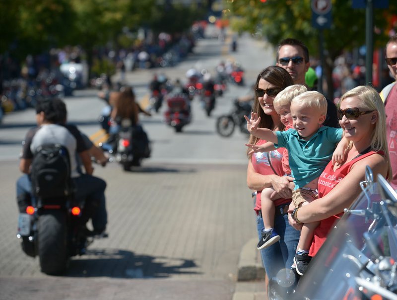 File photo/NWA Democrat-Gazette/ANDY SHUPE Colby Myers, 2, (center) and twin brother Emmett, wave at motorcycles in September 2018 while spending the day with their mother, Audra Myers (right) and friend Kim White, both of Rogers, during the Bikes, Blues &amp; BBQ motorcycle rally in Fayetteville. Organizers say the event's appeal has grown from its early days to a family friendly affair.