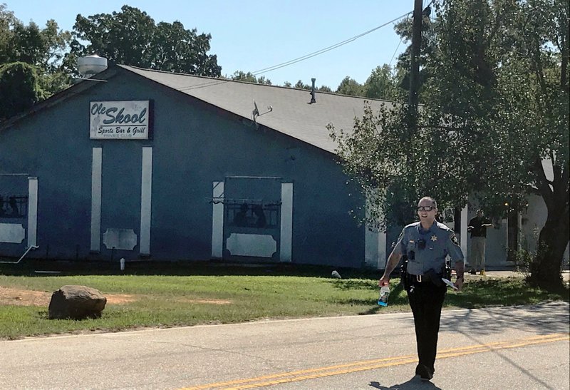 A Lancaster County Sheriff's deputy walks around the Old Skool Sports Bar and Grill, the scene of a shooting early in the morning, north of Lancaster, S.C. on Saturday, Sept. 21, 2019. Lancaster County Sherriff's Office said in a statement that the agency was investigating a fatal shooting that also injured several people. (Jessica Holdman/The Post And Courier via AP)