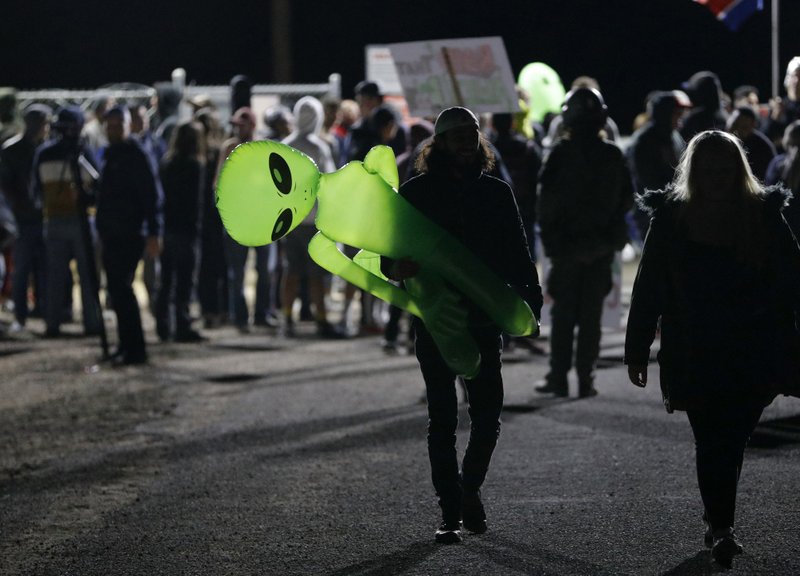 A mans holds an inflatable alien at an entrance to the Nevada Test and Training Range near Area 51 Friday, Sept. 20, 2019, near Rachel, Nev. (AP Photo/John Locher)