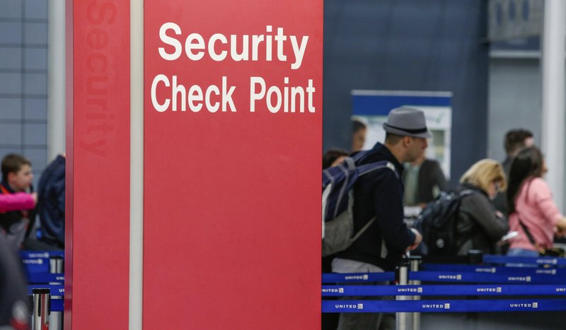 In this March 22, 2016 file photo, passengers check into their flights near a security checkpoint sign at O'Hare International Airport in Chicago. The arrest of an airline mechanic suspected of being sympathetic with terrorists and charged with sabotaging a jetliner has renewed fear about the "insider threat" to aviation security. (AP Photo/Teresa Crawford, File)