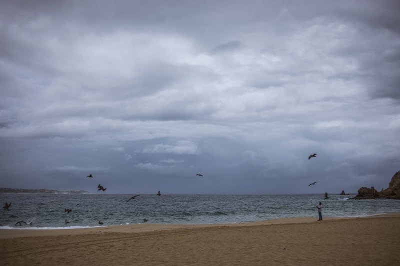 A tourist walks on the beach before the expected arrival of Hurricane Lorena, in Los Cabos, Mexico, Friday, Sept. 20, 2019. Hurricane Lorena neared Mexico's resort-studded Los Cabos area Friday as owners pulled their boats from the water, tourists hunkered down in hotels, and police and soldiers went through low-lying, low-income neighborhoods urging people to evacuate. (AP Photo/Fernando Castillo)