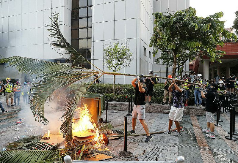 Pro-democracy demonstrators in Hong Kong use palm fronds and other items to set a fire Sunday during protests outside a mall.