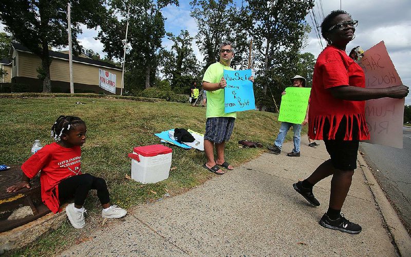 Bobbie Taylor (right), an organizer with Arkansas Renters United, stands with protesters and residents Sunday on the sidewalk outside the Spanish Valley Apartments on Baseline Road in Little Rock.