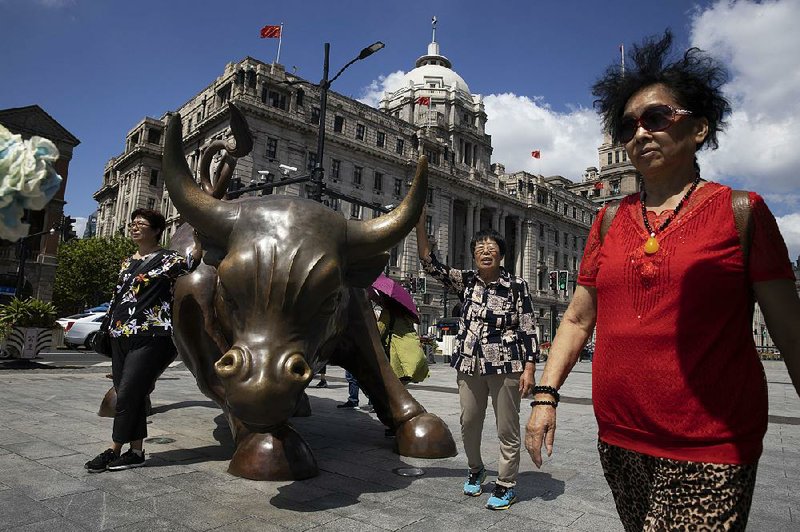 Visitors are seen Friday in Shanghai near the Bund Bull, an emulation of the Charging Bull statue on Wall Street in New York. China is heightening its monitoring of businesses, using data to grade companies and their owners.