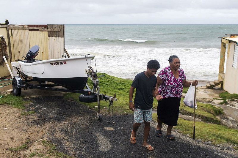 Irma Torres walks with her grandson Tuesday as they leave their home in the oceanfront community of El Negro in Yabucoa, Puerto Rico, in advance of Tropical Storm Karen. 