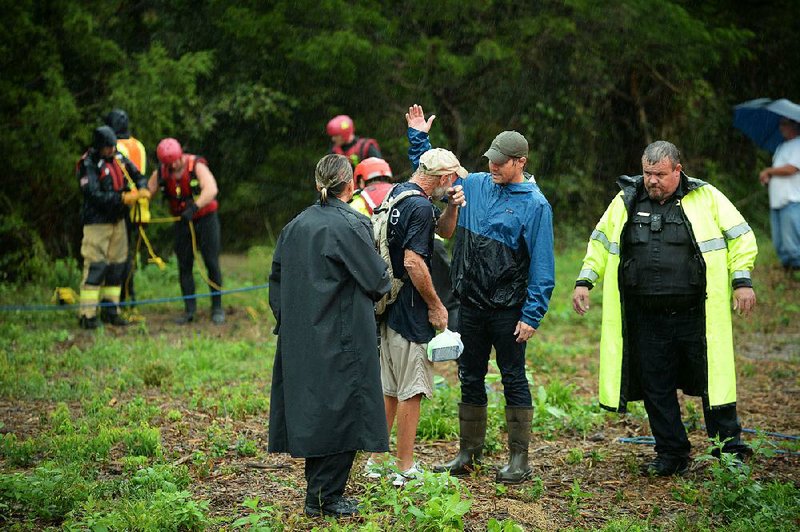 People comfort a man Tuesday after he was rescued from the rain-swollen Town Branch in Fayetteville. 