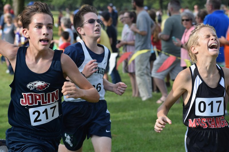 RICK PECK/SPECIAL TO MCDONALD COUNTY PRESS McDonald County seventh-grader Christian Howerton (017) strains at the finish line to beat Grey Edwards (217) of Joplin and Carter Allan of Fulbright to take ninth place at the McDonald County Junior High Cross Country Invitational held Sept. 19 at Elk River Golf Course in Noel.