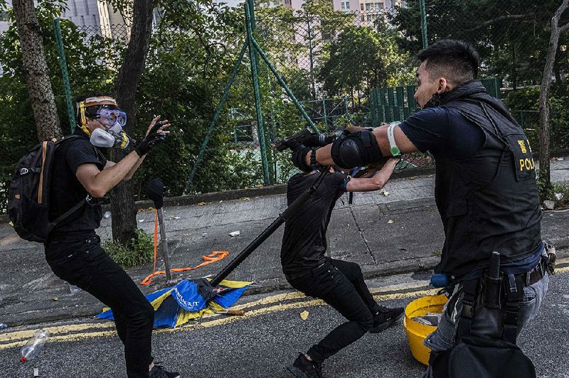 A police officer points his handgun at a protester Tuesday during one of several clashes around Hong Kong. More photos are available at arkansasonline.com/102march/ 