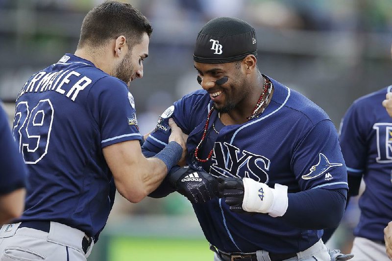 Yandy Diaz (right) of the Tampa Bay Rays is congratulated by teammate Kevin Kiermaier after hitting a leadoff home run in the first inning against the Oakland Athletics in the American League wild-card playoff game Wednesday night. Diaz added another home run in the third inning of the Rays’ 5-1 victory. 