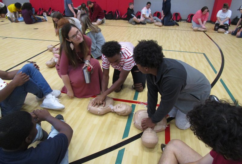 Magnolia teacher Julie Carter (left) helps MHS students learn CPR techniques at a recent assembly.