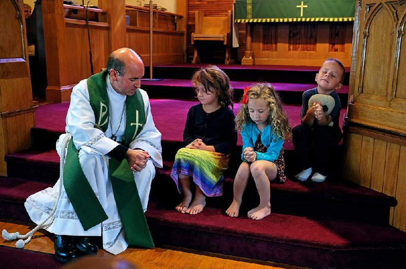 The Rev. Jason Felici prays with Olivia Caplinger; his daughter, Emma Felici; and Holden Puchany during a short time at the service where kids come to the front for a talk and prayer at Faith Lutheran Church in Franklin, W.Va. 