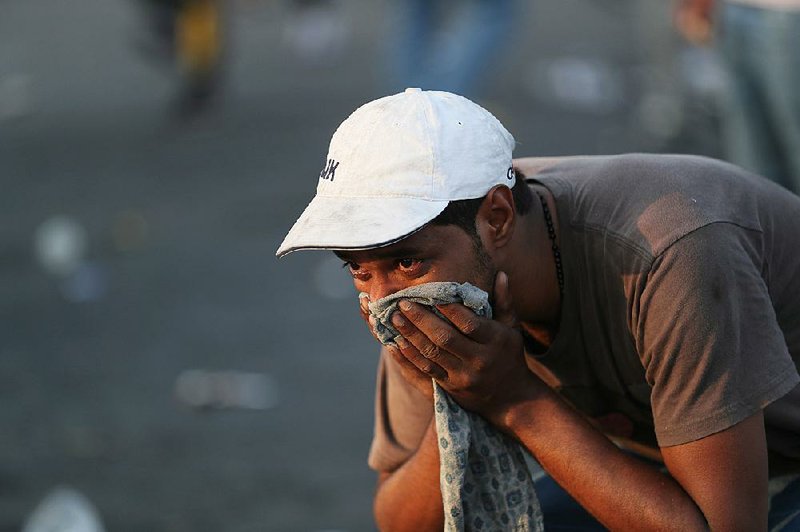An anti-government protester reacts to tear gas fired Thursday by security forces during a demonstration in Baghdad. 