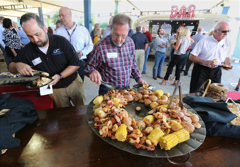 NWA Democrat-Gazette/DAVID GOTTSCHALK Charles Hester (center) with Cram-A-Lot selects shrimp Thursday at Shiloh Square during the annual Chickin, Peelin' &amp; Politickin' event in Springdale. Regional civic and business leaders have the opportunity to speak with national, state, regional and local political leaders and elected officials at the event organized by Springdale's Chamber of Commerce.
