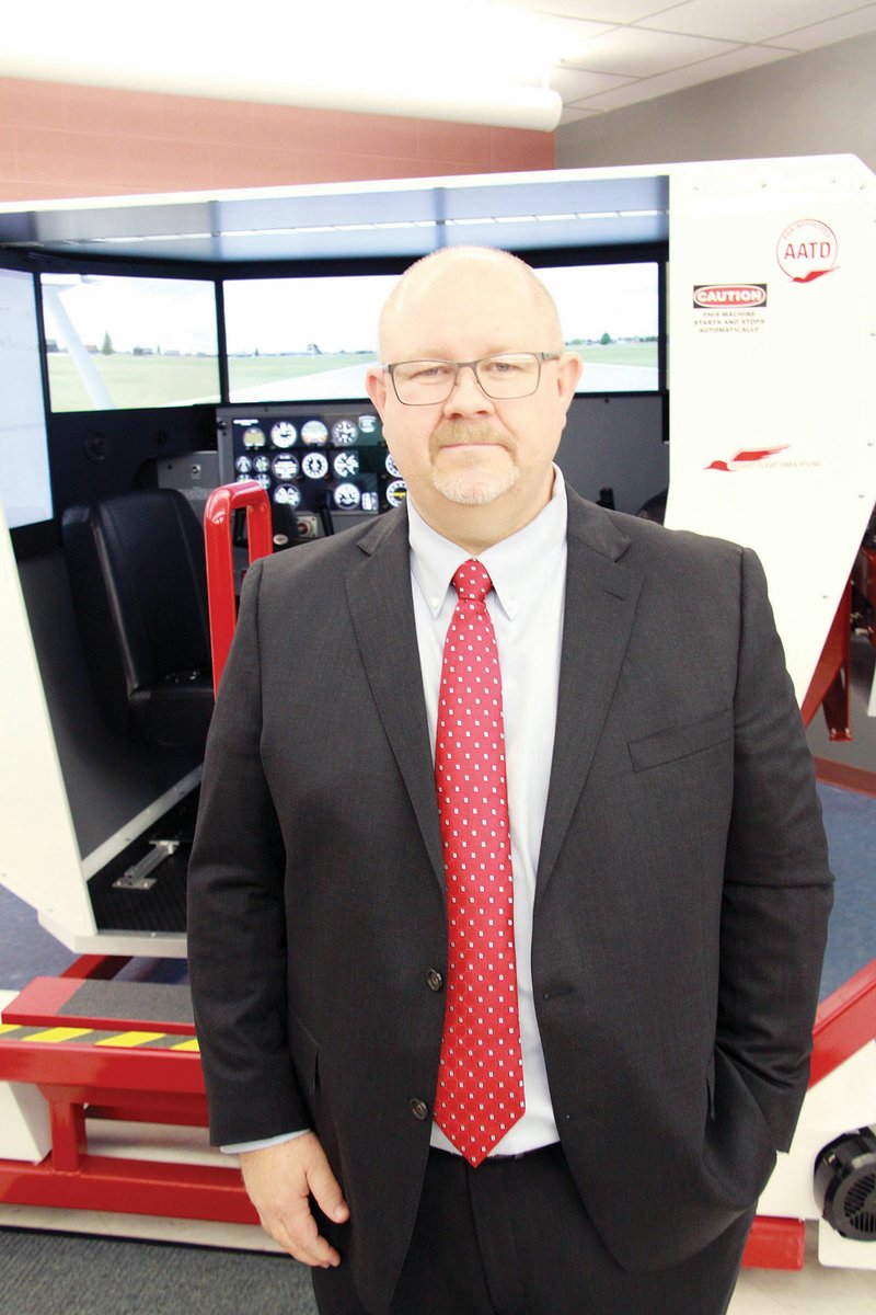 Troy Hogue, director of aviation at Henderson State University, stands in front of the Redbird full-motion flight simulator recently purchased through a grant from the Arkansas Department of Aeronautics.