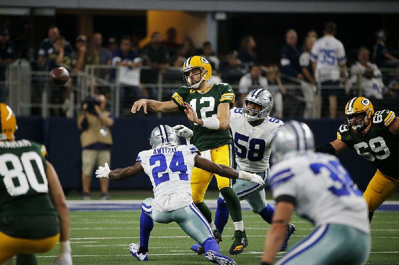 Green Bay’s Aaron Rodgers passes while under pressure from Dallas’ Chidobe Awuzie (24) and Robert Quinn (58) in the first half Sunday in Arlington, Texas. Rodgers guided the Packers back from their first loss as they held off a Cowboys rally for a 34-24 victory.