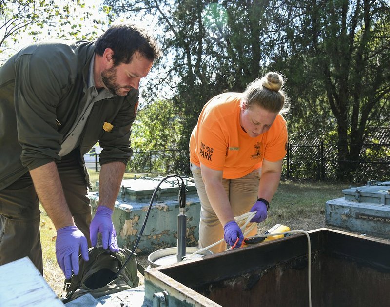 Kelly Sokolosky, former hydrologic technician with Hot Springs National Park, and Nathan Charlton, the park's new natural resource program manager, test the water in a spring in the park. - Photo by Grace Brown of The Sentinel-Record