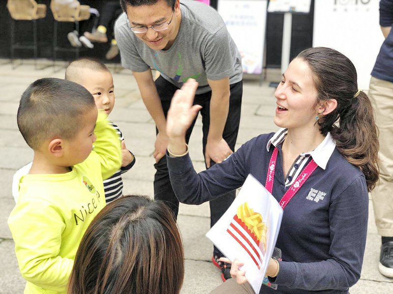 Southern Arkansas University alum Jacinda Passmore (right) high-fives her Chinese students while teaching in the city of Fuzhou.