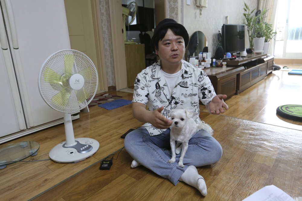 Jang Myung-jin holds his dog while talking about his YouTube channel at home in Seoul in this July photo. speaks during an interview at his house in Seoul, South Korea. Jang enjoys putting on funny wigs and hamming it up on his channel. (Photo by Ahn Young-Joon via AP)