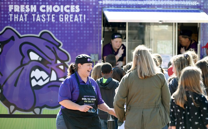 Amy Jefferson (left), assistant director of child nutrition at Fayetteville Public Schools, describes the choices Monday before being served from the Fayetteville Public Schools' Purple Dog Food Truck at McNair Middle School in Fayetteville. The truck offered an authentic Mexican meal Monday and will visit Holt Middle School on Wednesday. NWA Democrat-Gazette/DAVID GOTTSCHALK