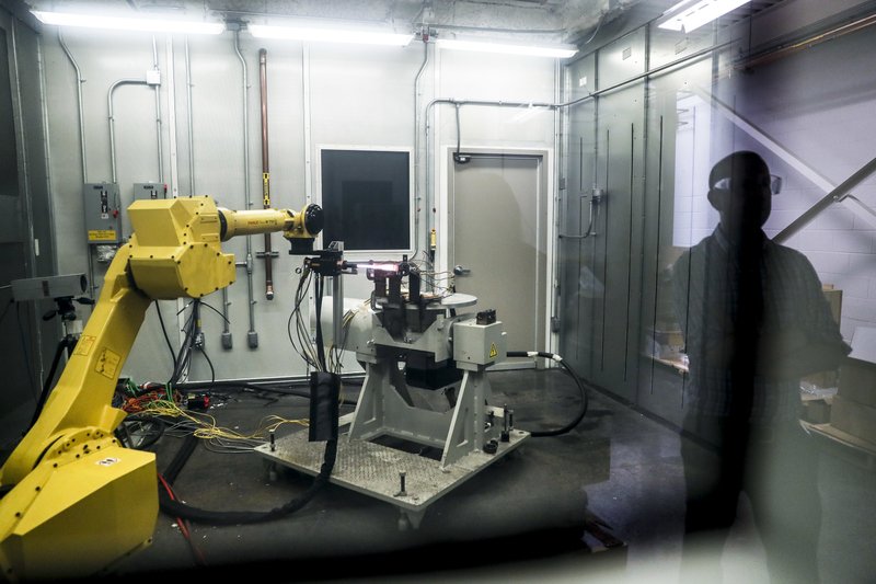 FILE - In this May 18, 2017, file photo, a robotic arm with a high-intensity blowtorch is remotely operated to test ceramic matrix composites, which make engines more durable, heat-resistant and efficient, at the General Electric Aviation plant in Evendale, Ohio. General Electric Co. said Monday, Oct. 7, 2019, that it will freeze its pension plan for about 20,700 salaried workers as part of its debt-cutting plan. (AP Photo/John Minchillo, File)