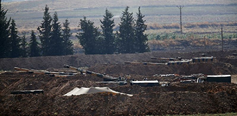 Turkish soldiers with artillery pieces hold their positions Tuesday near the border with Syria in Sanliurfa province. Turkey has been building up reinforcements on its side of the border in preparation for an assault on Kurdish fighters in Syria. More photos are available at arkansasonline.com/109border 