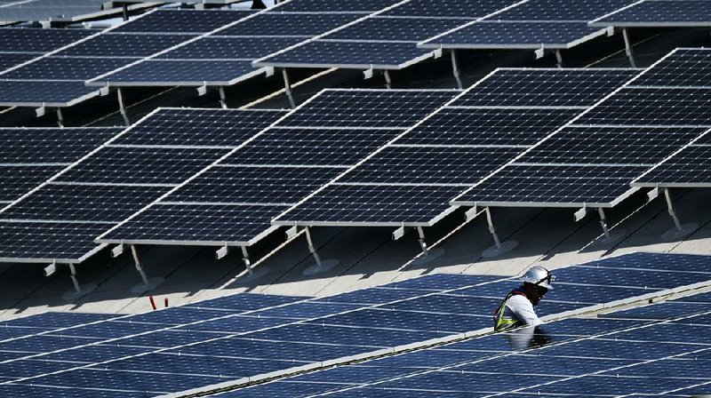 A worker helps install solar panels in August at the Van Nuys Airport in Los Angeles. U.S. producer prices fell in September, adding to signs of tame inflation pressures. 