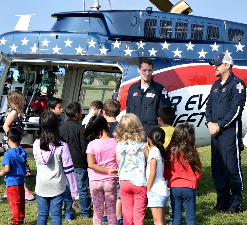 Westside Eagle Observer/MIKE ECKELS Andrew Chaffin (center), flight nurse, and Eril Brotherton (right), pilot, explain the controls of their Air Evac helicopter to students at Northside Elementary during the Decatur District's Fire Safety Day on Friday.