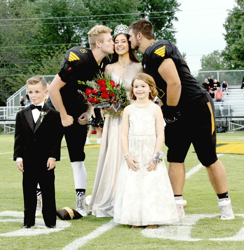 MARK HUMPHREY ENTERPRISE-LEADER/Prairie Grove Homecoming queen Olivia Stroud receives congratulatory kisses from senior captains Graham Guenther (left) and Hayden Black while attendants, Barrett Watson and Ella Davis, stand by.