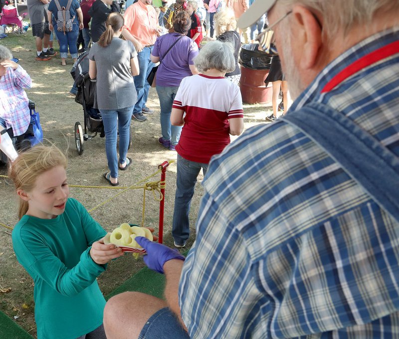 LYNN KUTTER ENTERPRISE-LEADER Carlos Reed hands over a bowl of fresh apple slices to this young lady at the 44th Arkansas Apple Festival. Many festival visitors lined up to enjoy the apple slices. Reed was one of many people who volunteered with the three-day event. Committee members reported a great turnout on Friday and Saturday. Sunday's rainy weather affected attendance. See more photos on pages 6A and 7A.