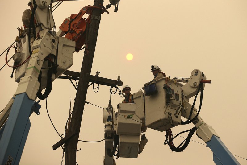 FILE - In this Nov. 9, 2018, file photo, Pacific Gas &amp; Electric crews work to restore power lines in Paradise, Calif. Two years to the day after some of the deadliest wildfires tore through Northern California wine country, two of the state's largest utilities were poised Tuesday, Oct. 8, 2019, to shut off power to more than 700,000 customers in 37 counties, in what would be the largest preventive shut-off to date as utilities try to head off wildfires caused by faulty power lines. (AP Photo/Rich Pedroncelli, File)