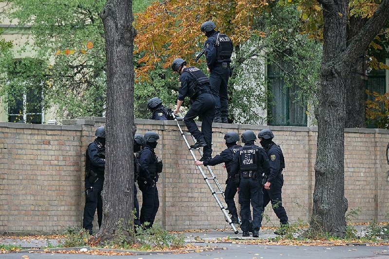 Police cross over a wall at the scene of Wednesday’s fatal shooting in Halle, Germany. More photos are available at arkansasonline.com/1010police/ 
