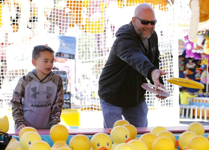 Zach Branch of Rison (top left) tries to toss a ring around a duck while his son, Bryant, waits for the prize; during last year's well-attended Arkansas State Fair. Democrat-Gazette file photo/Thomas Metthe 