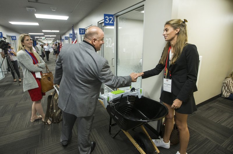 Sarah Machann (from left), executive assistant, and Leigh Meyers, CEO and president, with Encore Industrial based in Houston, Texas, stop to talk to Mollie Thorsen, COO of The Little Burros based in Washington, about their Burro Buddy wheelbarrow accessory between pitch meetings Wednesday, June 19, 2019, during day two of Walmart's annual Open Call event at the Walmart Home Office in Bentonville.